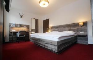 a hotel room with a large bed and a desk at stadthotel miya in Bad Mergentheim