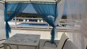 a table and chairs on a balcony with a blue curtain at Luštica Apartments in Luštica