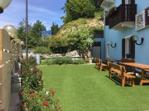 un patio con bancos, una mesa y flores en Hotel Romanda, en Lavarone