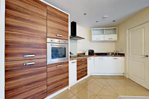 uma cozinha com armários brancos e painéis de madeira em Blue Sky Apartments @Wallis Square, Farnborough em Farnborough