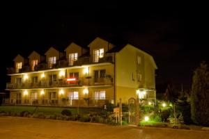 a large yellow building with lights in the night at Dom Wczasowy Mrokon in Grzybowo