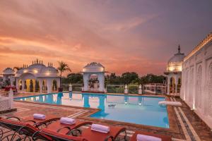 una piscina en un complejo con una puesta de sol en el fondo en Hotel Rajasthan Palace, en Jaipur