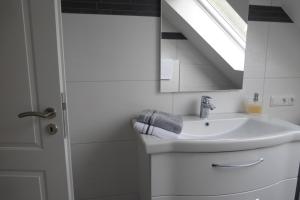 a white bathroom with a sink and a window at Ferienwohnung am Eifelsteig in Roetgen