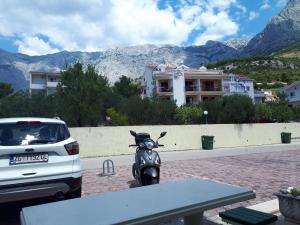a motorcycle parked in a parking lot next to a car at Apartman Adriatic Sea in Promajna