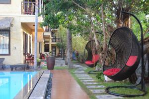 a swimming pool with two swing chairs next to a house at Rang Garden Bungalow in Mui Ne