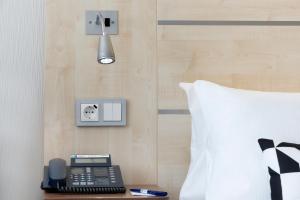 een telefoon op een tafel naast een bed bij Holiday Inn Express Singen, an IHG Hotel in Singen