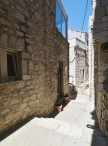 an alley in an old stone building with potted plants at Hostel Sv. Lovre in Šibenik