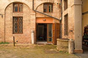 シエナにあるApartment in the historic city center of Sienaの開口扉のある古いレンガ造りの建物