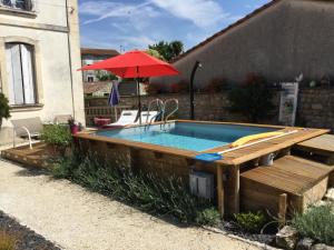 a pool with a red umbrella and chairs and a table at Saint James House in Pons