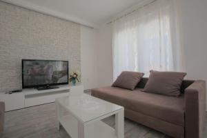 ein Wohnzimmer mit einem Sofa und einem TV in der Unterkunft Apartman Slavko in Seget Vranjica