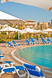a swimming pool with blue chairs and umbrellas at Grand Ocean El Sokhna in Ain Sokhna