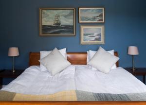 a bedroom with a white bed with three pictures on the wall at Hotell Blå Blom in Gustavsberg