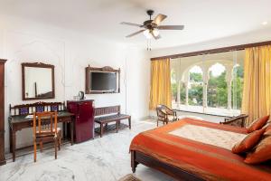 a bedroom with a bed and a desk and a television at Hotel Rajasthan Palace in Jaipur