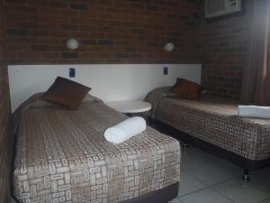 a hotel room with two beds and a table at Cattleman's Rest Motor Inn in Charters Towers