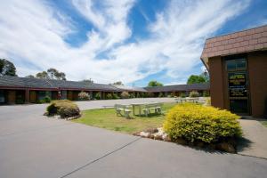 a building with two picnic tables outside of it at Golden Grain Motor Inn in Horsham