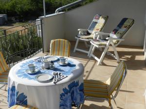 a table with plates and cups and chairs on a balcony at Apartmani Lucija Jurković in Malinska