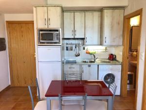una cocina con armarios blancos y una mesa roja en Mirador Castillo La Iruela, en Cazorla