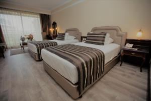 a hotel room with two beds and a desk at Karaca Hotel in Izmir