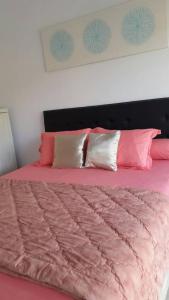 Una cama rosa con almohadas rosas y blancas. en Villa Jidah, en Gegarbensang