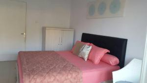 Un dormitorio con una cama rosa con sábanas y almohadas rosas. en Villa Jidah, en Gegarbensang