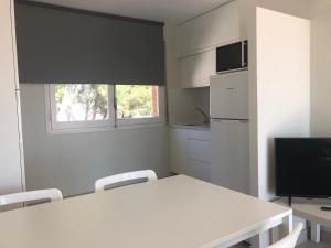 a white kitchen with a white table and chairs at SunAndBed ATICO FARO in Salou