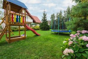 a yard with a playground with a slide and swings at FOR YOU dom dla 10 osób in Białogóra