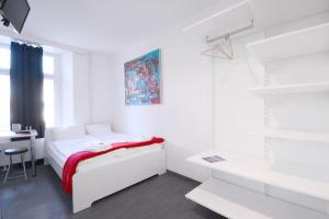 a white bedroom with a bed and a desk at HITrental Station Apartments in Lucerne