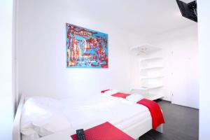 a bedroom with a white bed with a painting on the wall at HITrental Station Apartments in Lucerne