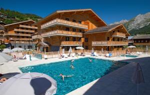 - une piscine en face d'un hôtel avec des personnes dans l'établissement Hôtel Prestige Odalys Le Chamois, à La Clusaz