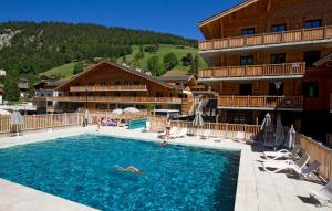 ein Hotel mit einem Pool vor einem Gebäude in der Unterkunft Résidence Prestige Odalys Mendi Alde in La Clusaz