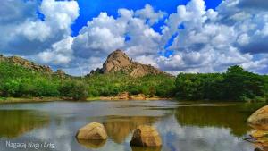 a river with rocks in front of a mountain at Hotel Ravi Mayur International in Chitradurga