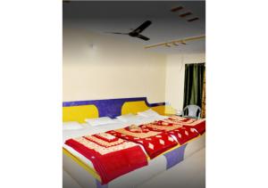 een slaapkamer met een bed met een rode en gele sprei bij Hotel Arihant in Pachmarhī