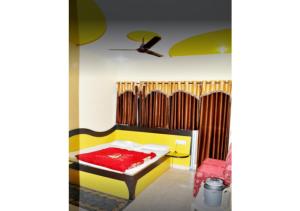 een slaapkamer met een geel en rood bed en een plafond bij Hotel Arihant in Pachmarhī