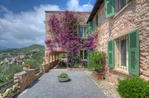 un edificio de piedra con persianas verdes y flores púrpuras en Villa Sole en Borgio Verezzi