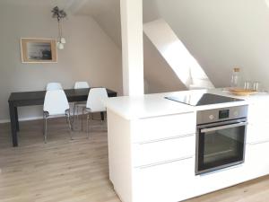 uma cozinha com armários brancos e uma mesa com cadeiras em Apartments Thommen Lohengrinstr em Nurembergue