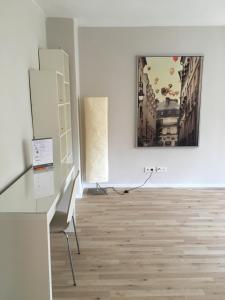 a white room with a desk and a painting on the wall at Apartments Thommen Lohengrinstr in Nürnberg +5 photos