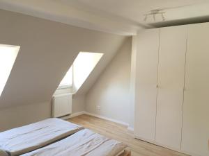 a white bedroom with a bed and a window at Apartments Thommen Lohengrinstr in Nürnberg
