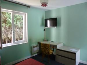 a green room with a desk and a window at Hotel Restaurant du Moulin de Barette in Blavozy