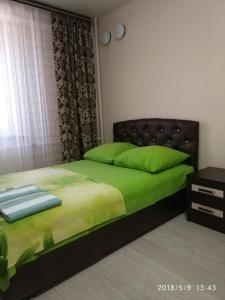 ヴォログダにあるApartment on Marshala Koneva 26のベッドルーム1室(緑色のベッド1台、黒いヘッドボード付)