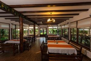 a restaurant with tables and chairs and windows at Pensiunea Restaurant Vándor in Cîmpu Cetăţii