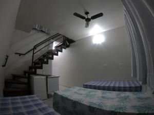 een slaapkamer met een plafondventilator en een trap bij Recanto Duas Peras in Caraguatatuba