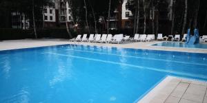 una gran piscina azul con sillones blancos en Apartament Aquamarine Polanki en Kołobrzeg