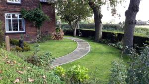 un jardín con una casa de ladrillo y una pasarela en The School House en Warrington