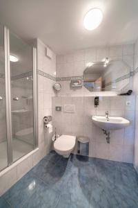 a bathroom with a toilet and a sink and a shower at City Hotel Hilden in Hilden