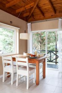 a dining room with a wooden table and white chairs at Plenilunio Mar de las Pampas in Mar de las Pampas