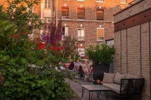un gruppo di persone seduti su un patio con piante di L'Imprimerie Hôtel a Clichy