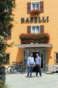 two men standing in front of a building at Raselli Sport Hotel in Poschiavo