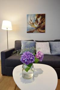 a vase with purple flowers on a table in a living room at Piłsudskiego In City Apartments in Krakow