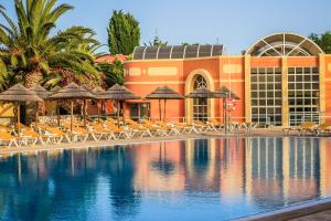 a resort with a swimming pool with chairs and umbrellas at Colina Village in Carvoeiro +47 photos
