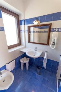 bagno piastrellato blu con lavandino e specchio di Masseria Ruri Pulcra a Patù